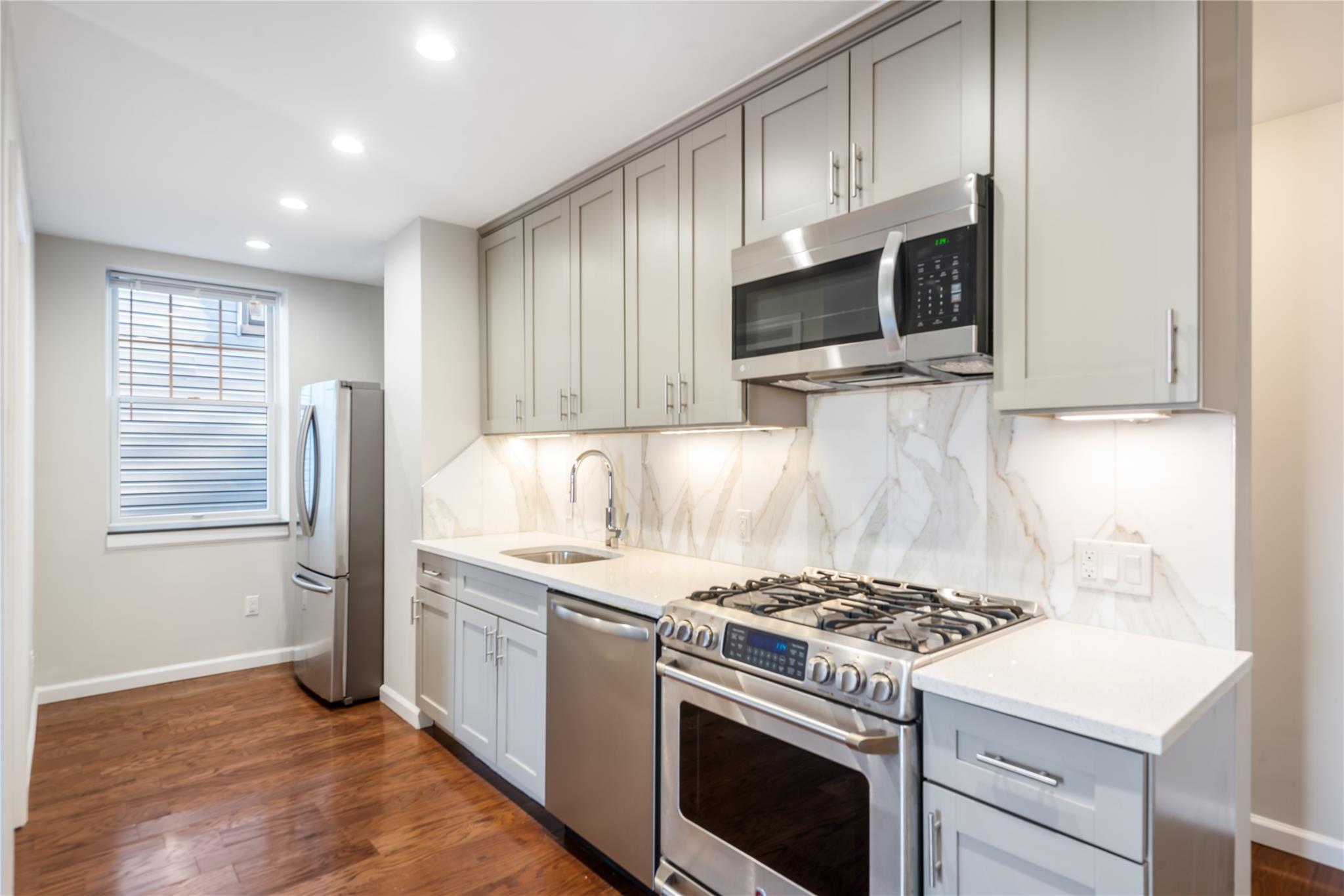 a kitchen with stainless steel appliances a stove a microwave and a sink