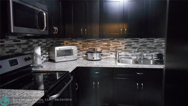 a kitchen with stainless steel appliances granite countertop a sink stove and microwave