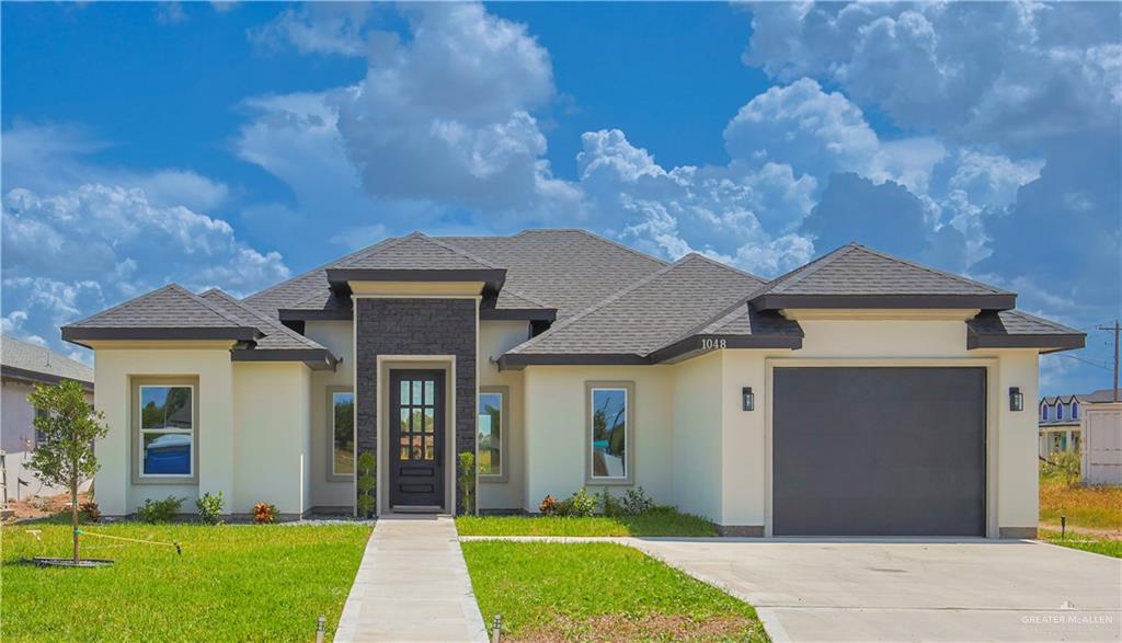 View of front of house with a garage and a front lawn