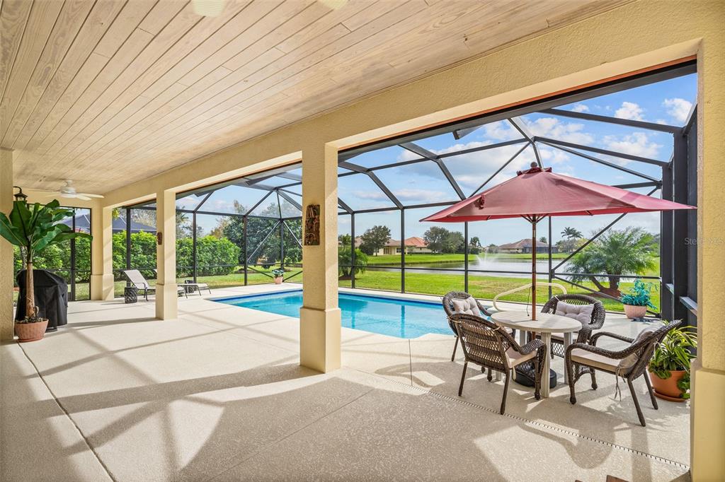 a view of pool with table and chairs under an umbrella