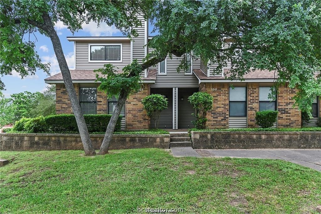 front view of house with a yard and a large tree