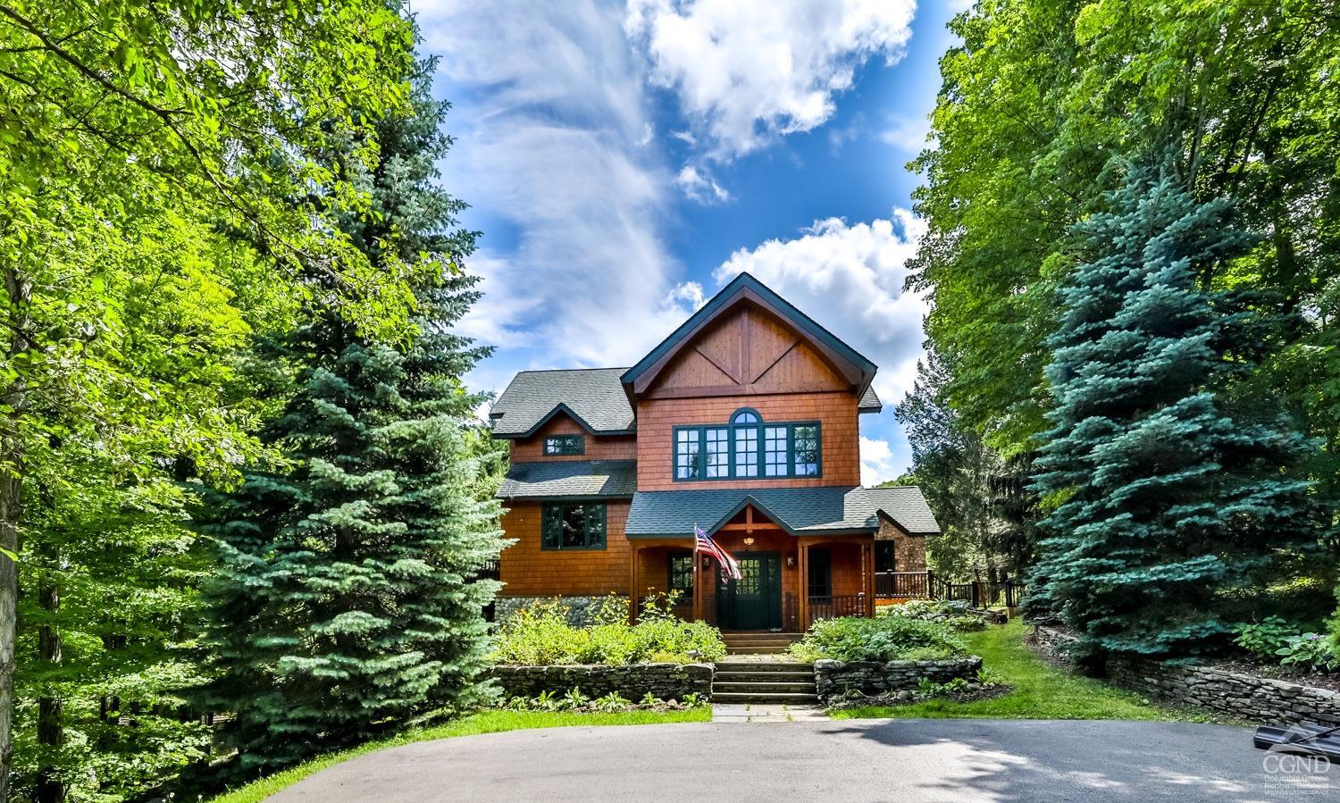 a front view of a house with yard and trees around