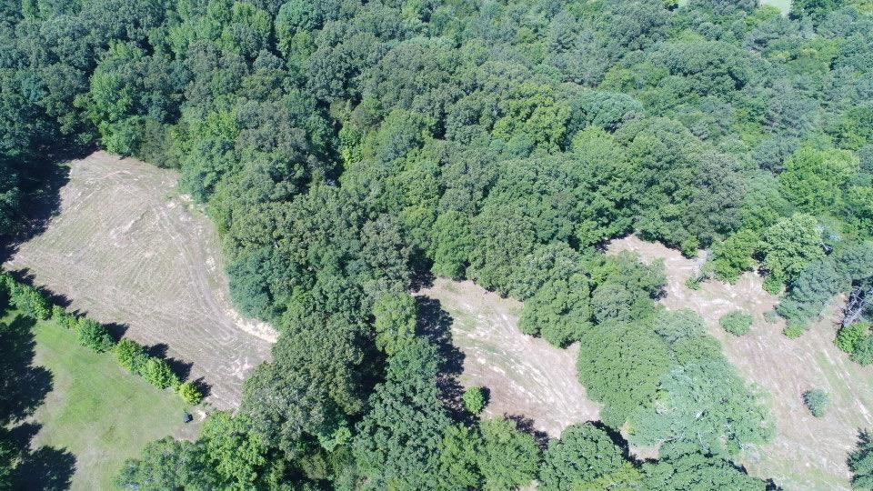 an aerial view of residential house with outdoor space and trees all around