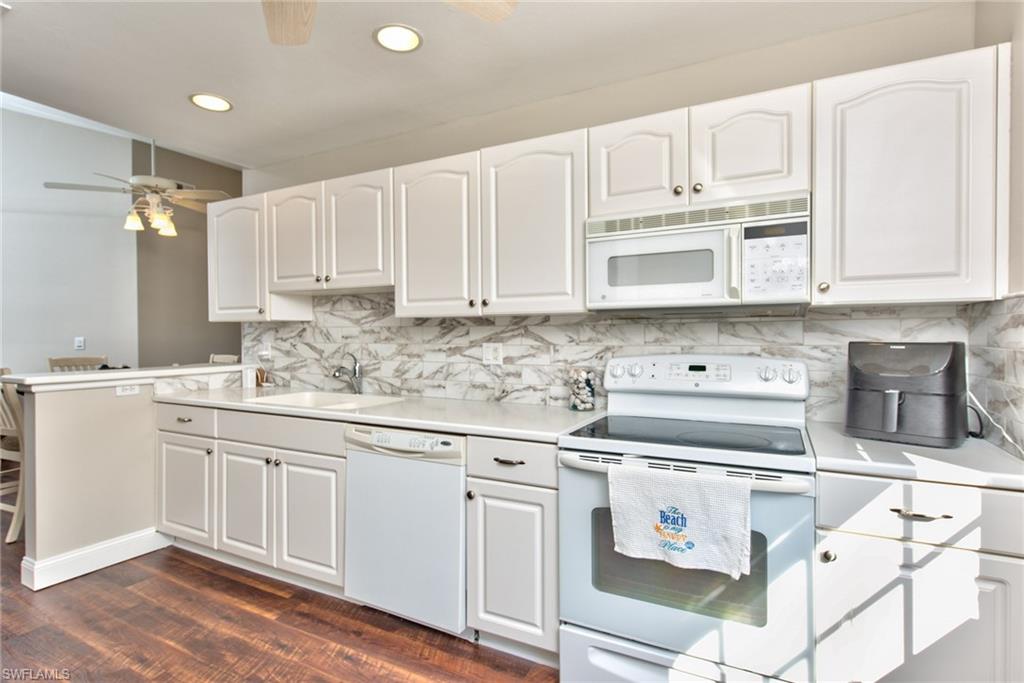 a kitchen with granite countertop white cabinets and white appliances