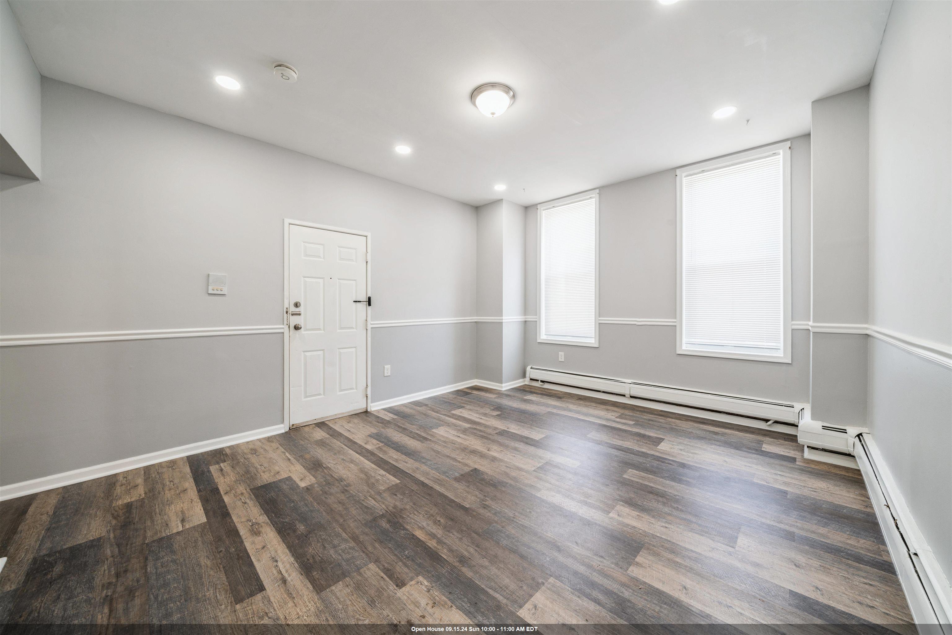 an empty room with wooden floor and windows