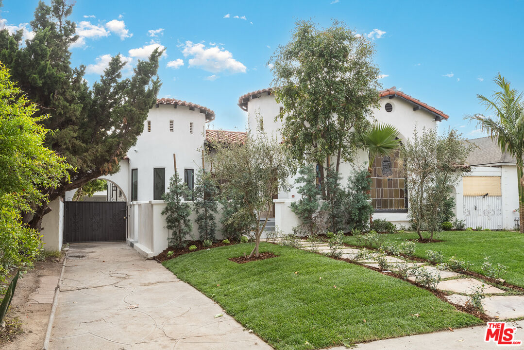 a front view of a house with a garden and trees