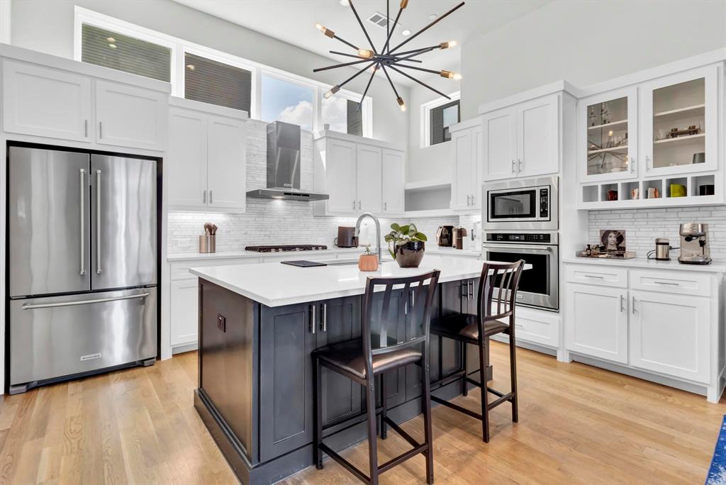 a kitchen with a refrigerator a stove a sink and white cabinets with wooden floor