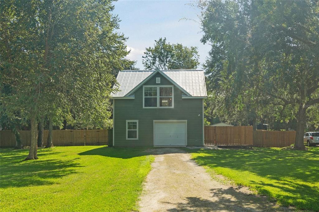 a front view of house with yard and trees in the background