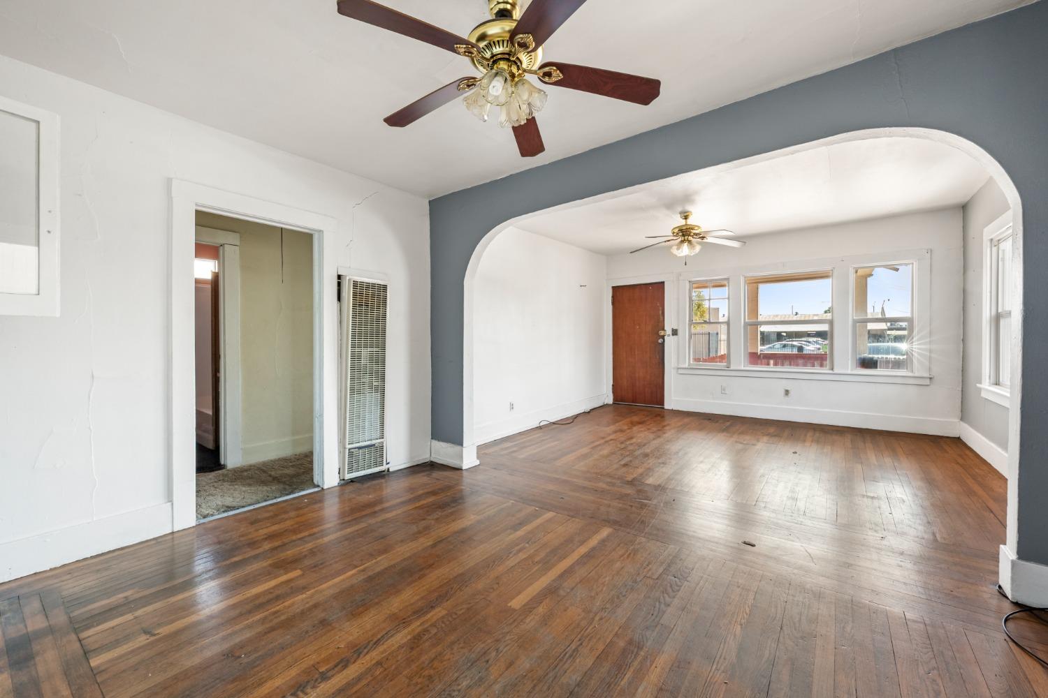 a view of an empty room with window and wooden floor