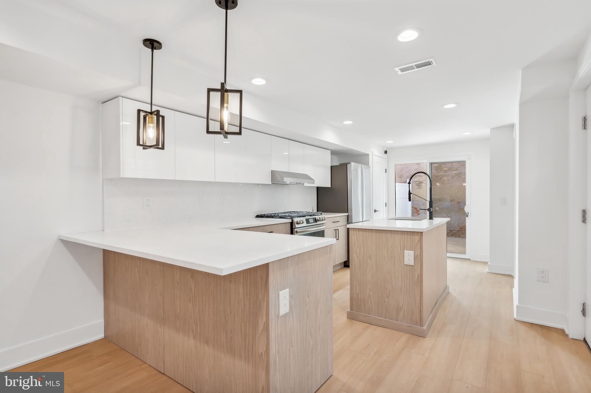 a kitchen with kitchen island a sink stainless steel appliances and wooden floor