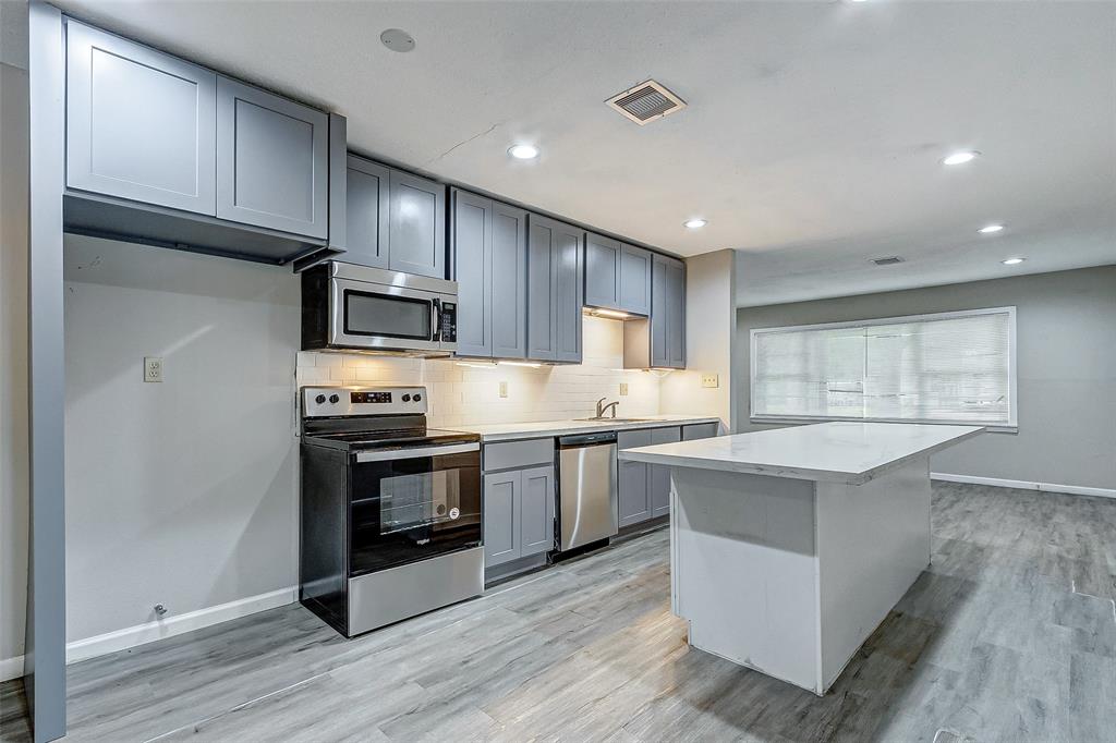 a kitchen with stainless steel appliances granite countertop a stove top oven a sink dishwasher and a refrigerator