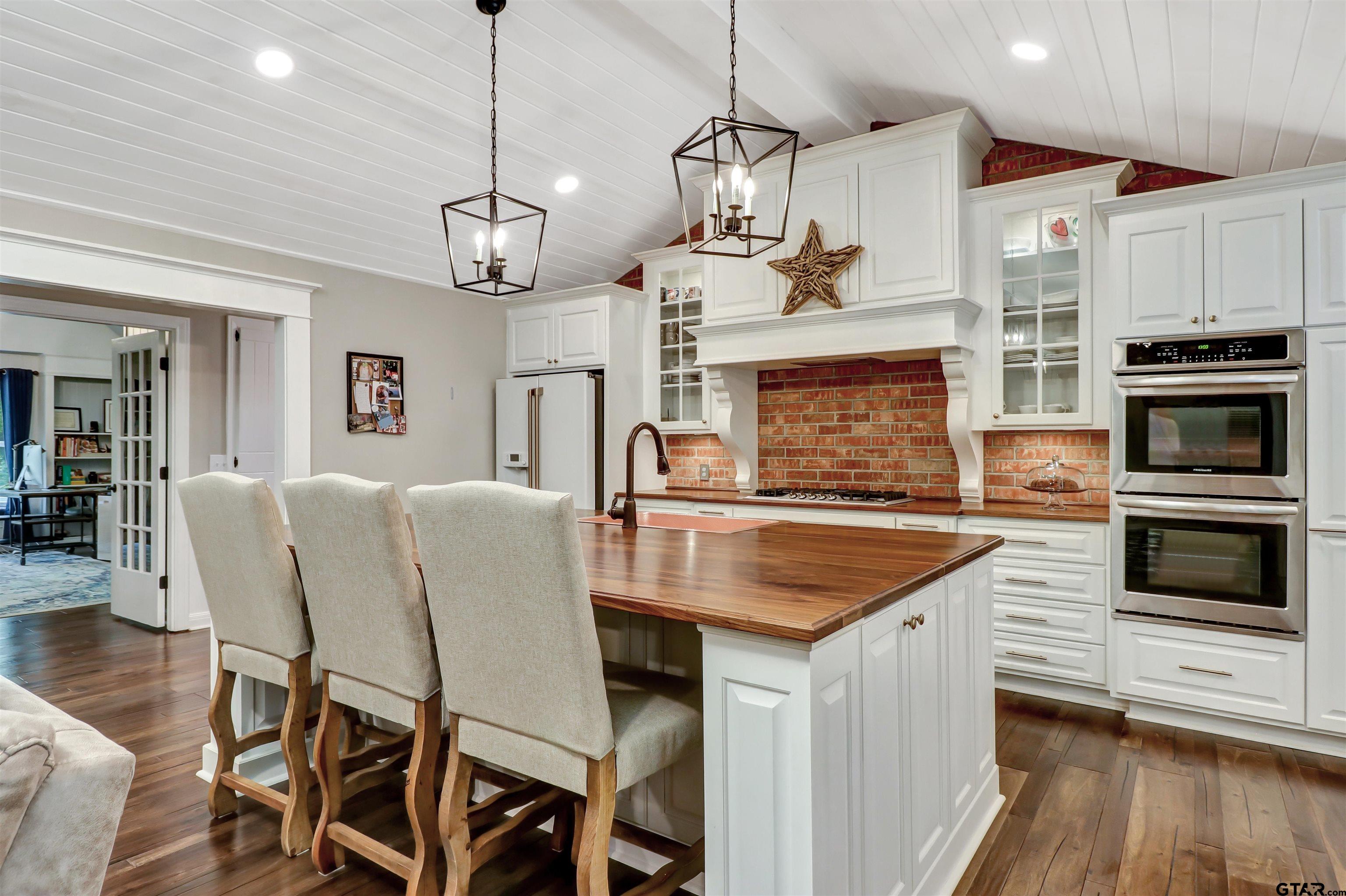 a kitchen with a table chairs stainless steel appliances and wooden floor