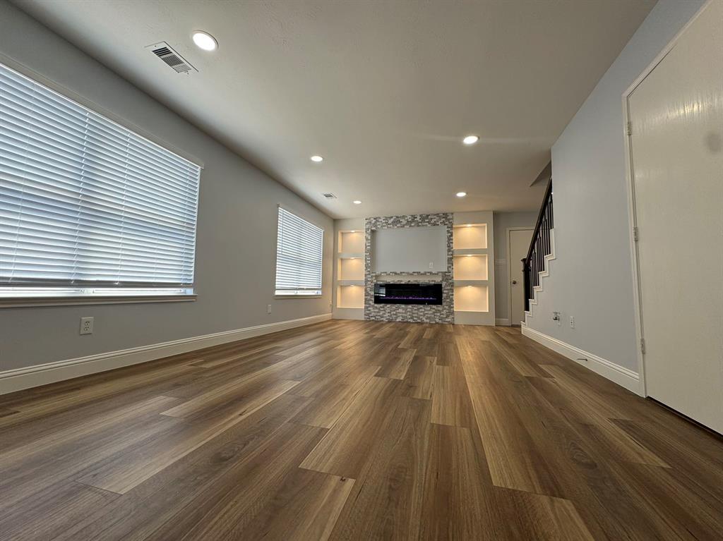 a view of empty room with wooden floor and window