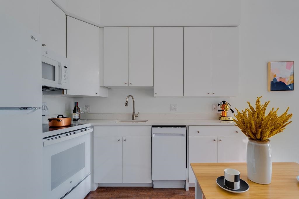 a kitchen with stainless steel appliances white cabinets and a wooden floor