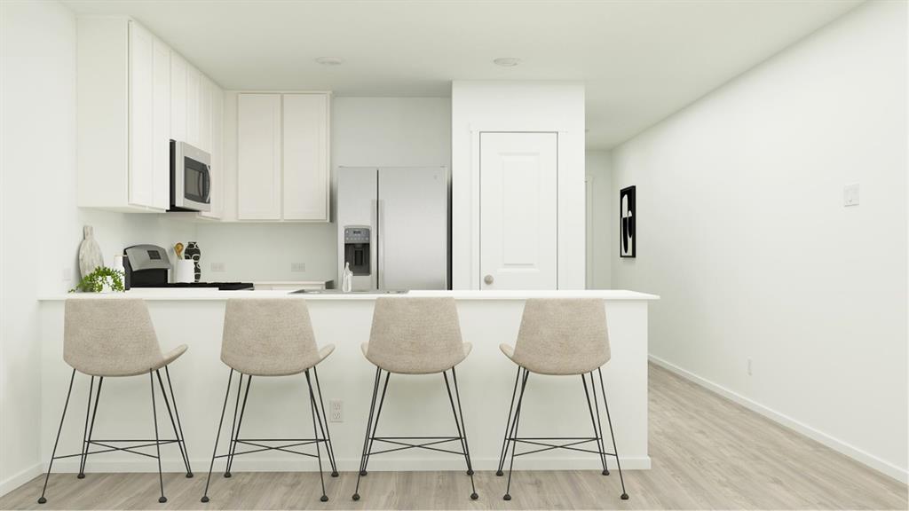 a kitchen with stainless steel appliances granite countertop a dining table chairs and a refrigerator