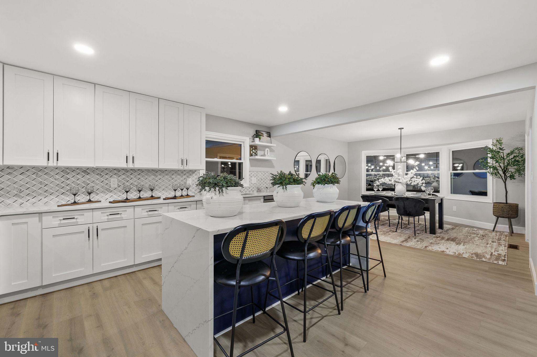 a kitchen with stainless steel appliances granite countertop a stove a sink dishwasher and a dining table with white cabinets