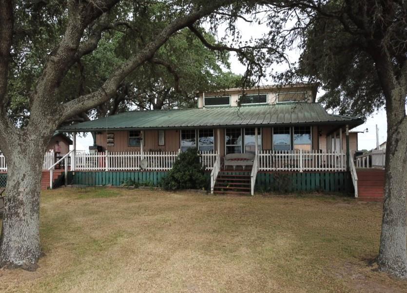 a view of a house with a backyard and a large tree