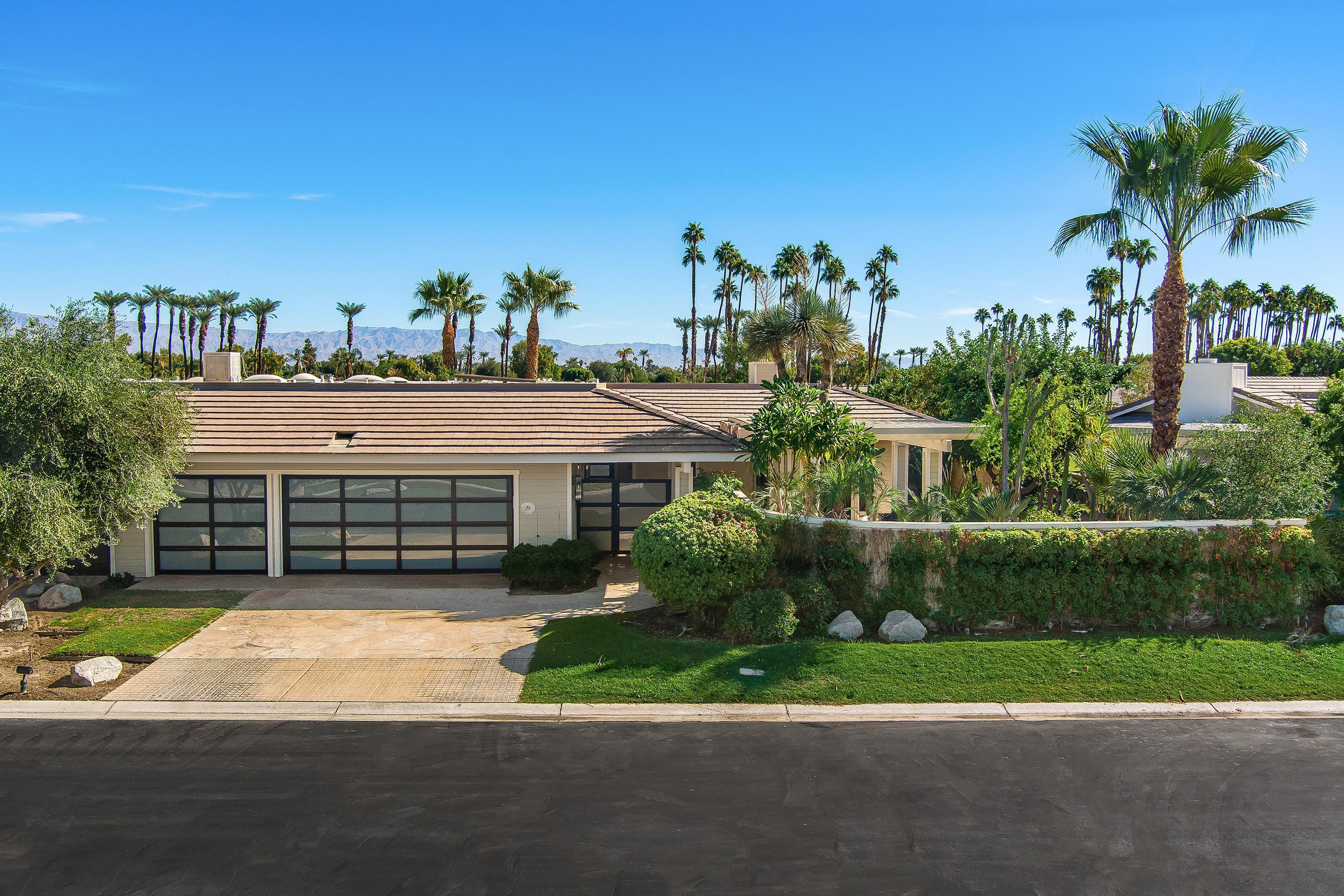 a view of a house with a yard and palm trees