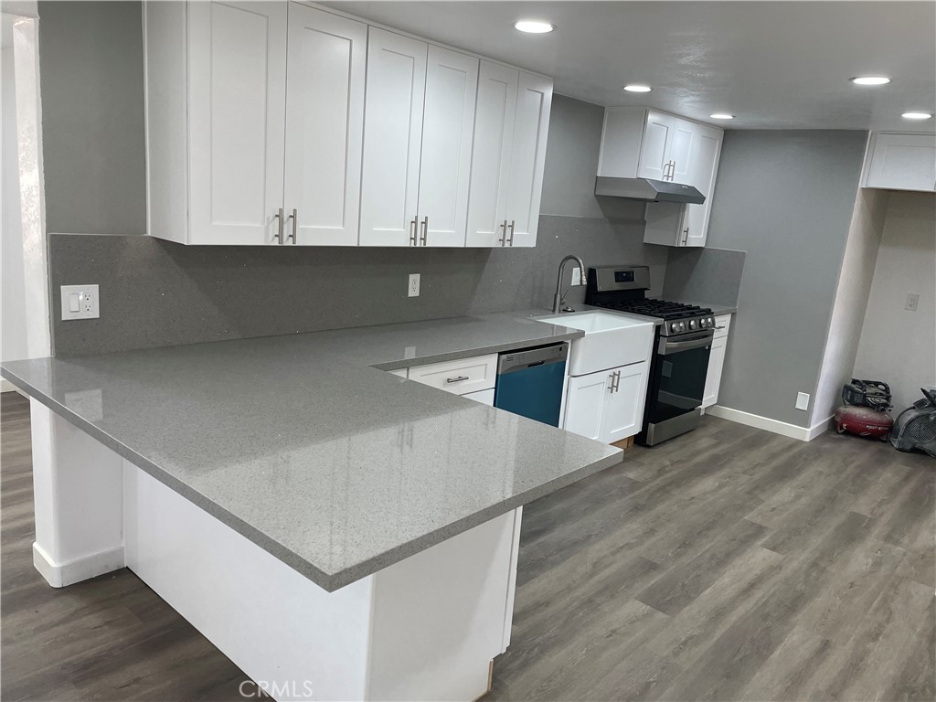 a kitchen with stainless steel appliances white cabinets and wooden floor