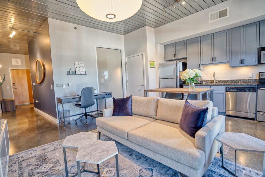 a living room with stainless steel appliances kitchen island granite countertop furniture and a wooden floor