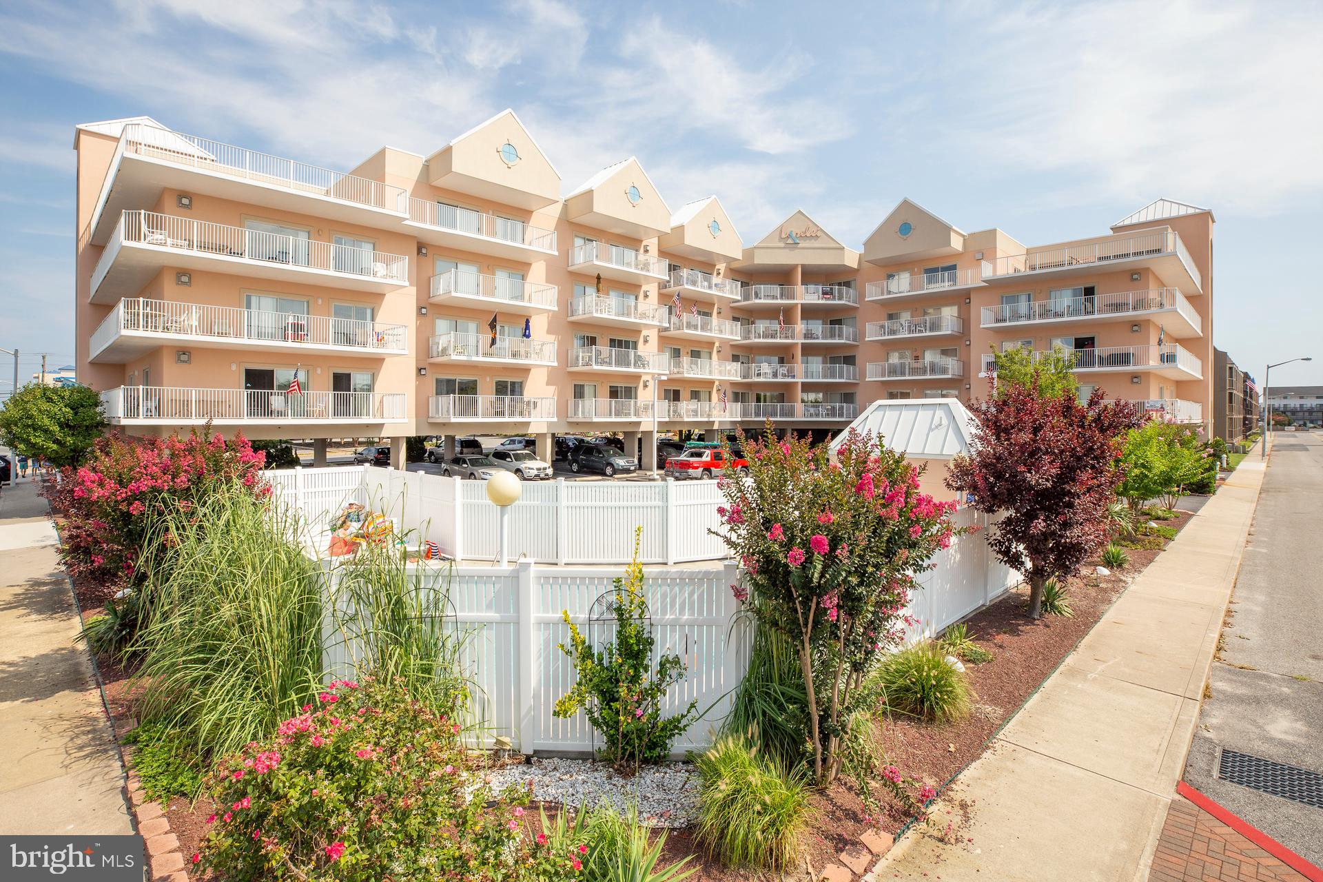 a front view of a multi story residential apartment building with yard and retail shops