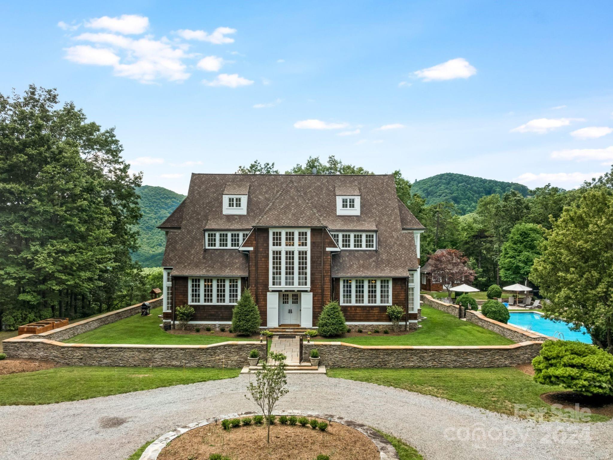 a view of a big house with a big yard and large trees