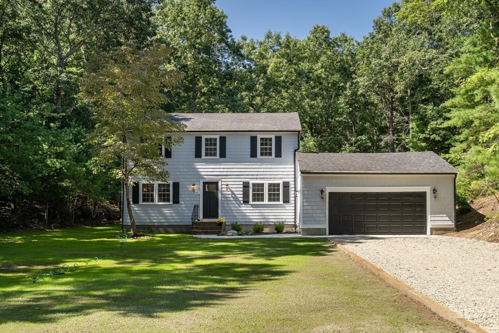 a front view of a house with a garden and trees