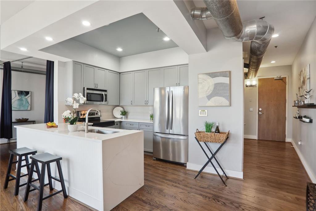 a kitchen with stainless steel appliances granite countertop a refrigerator a stove top oven a sink dishwasher a dining table and chairs with wooden floor