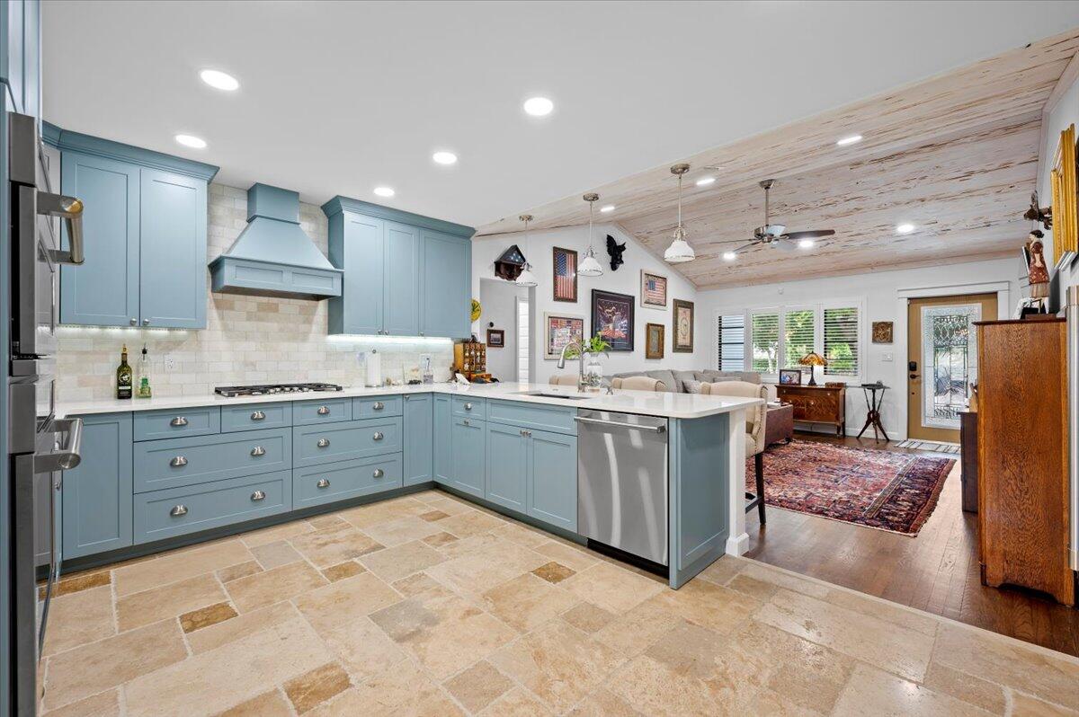 a kitchen with stainless steel appliances kitchen island granite countertop a refrigerator and a sink