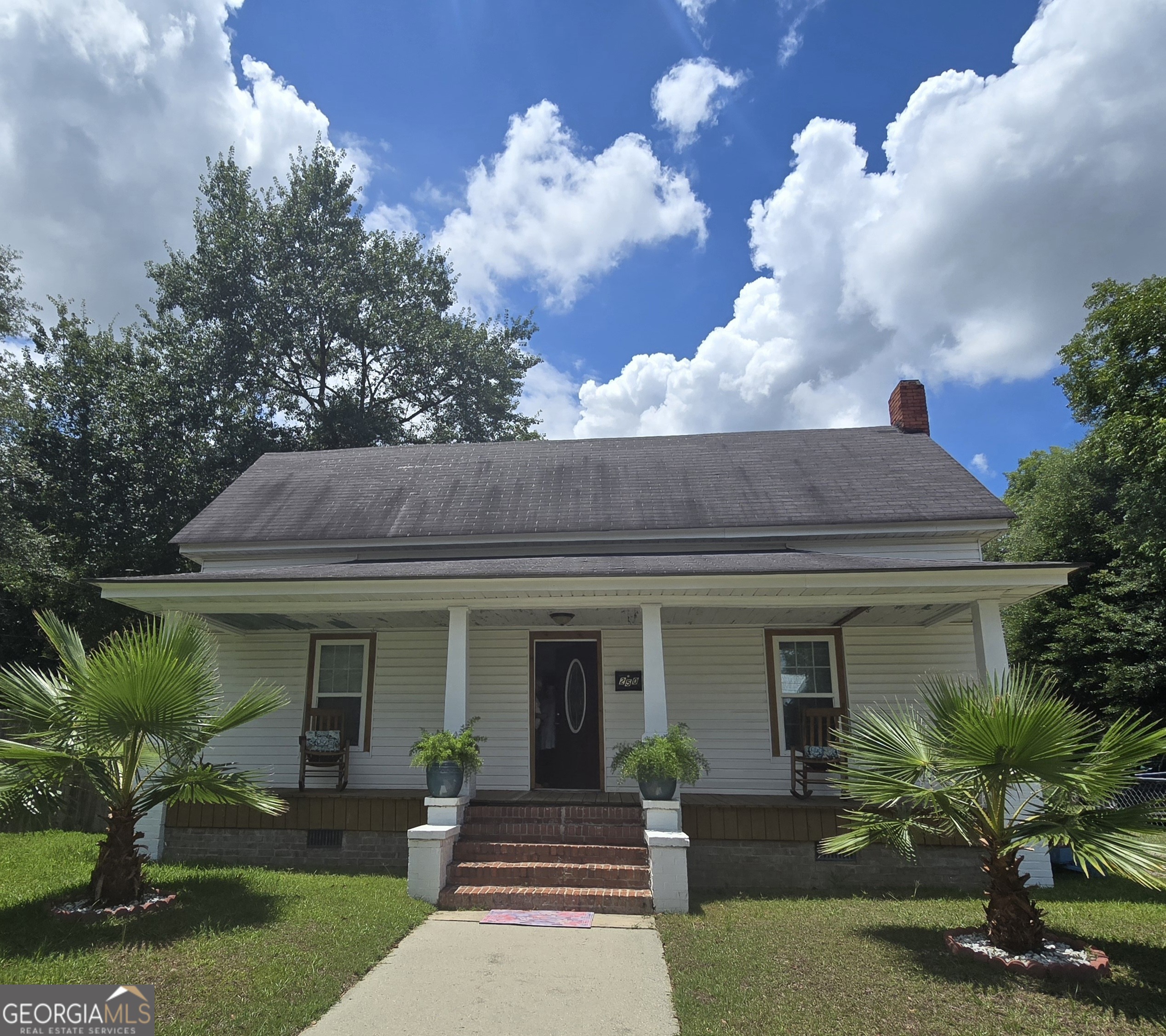 a view of a house with a yard potted plants and a table