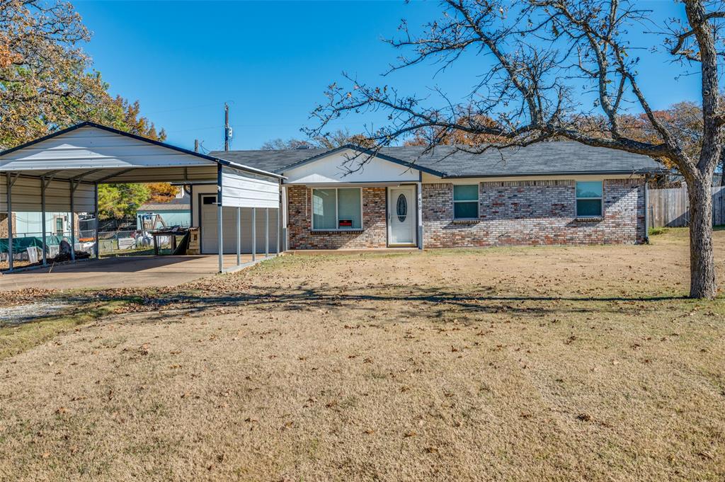 View of front facade featuring a front lawn and a carport