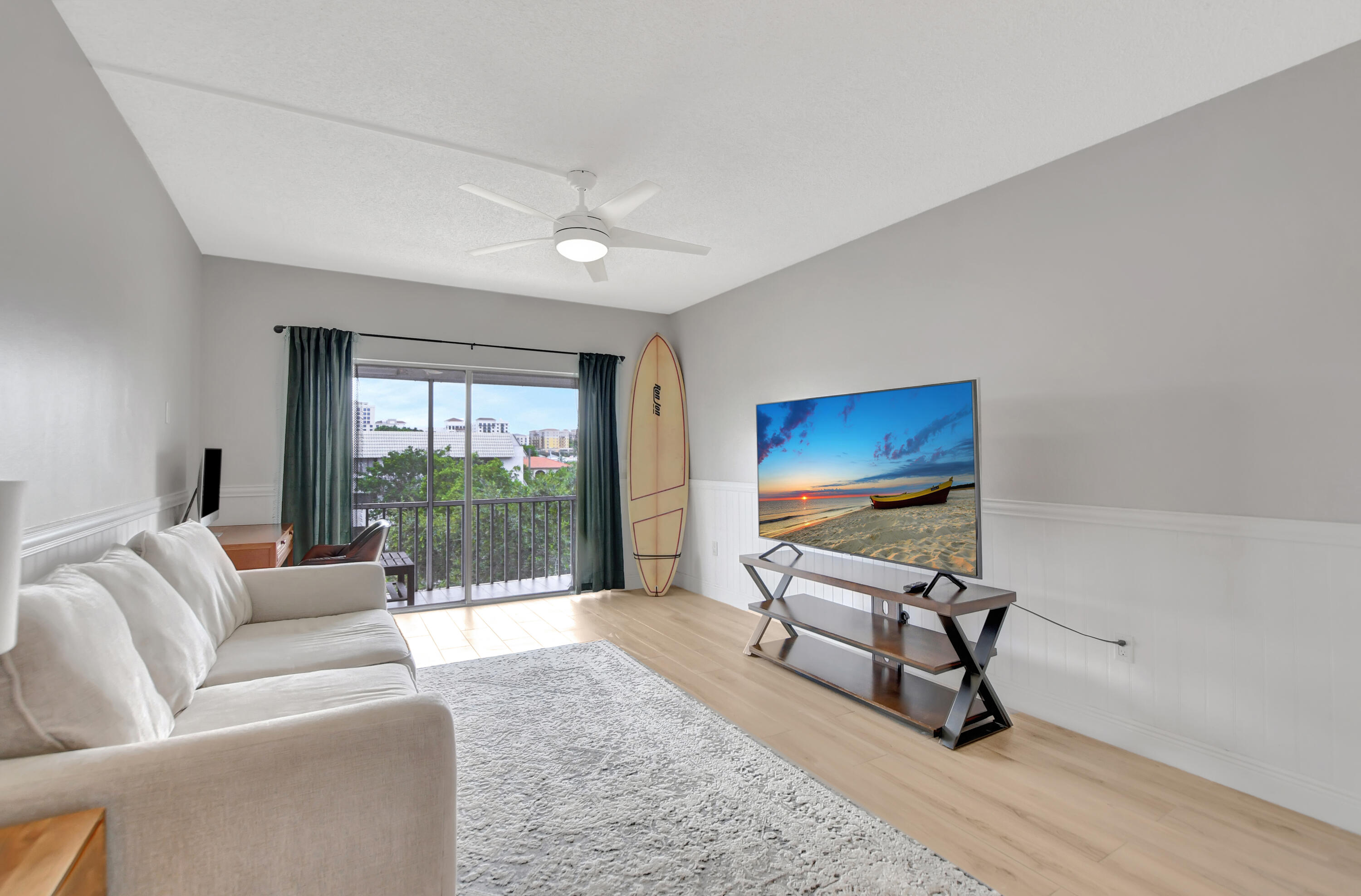 a living room with furniture a floor to ceiling window and a flat screen tv