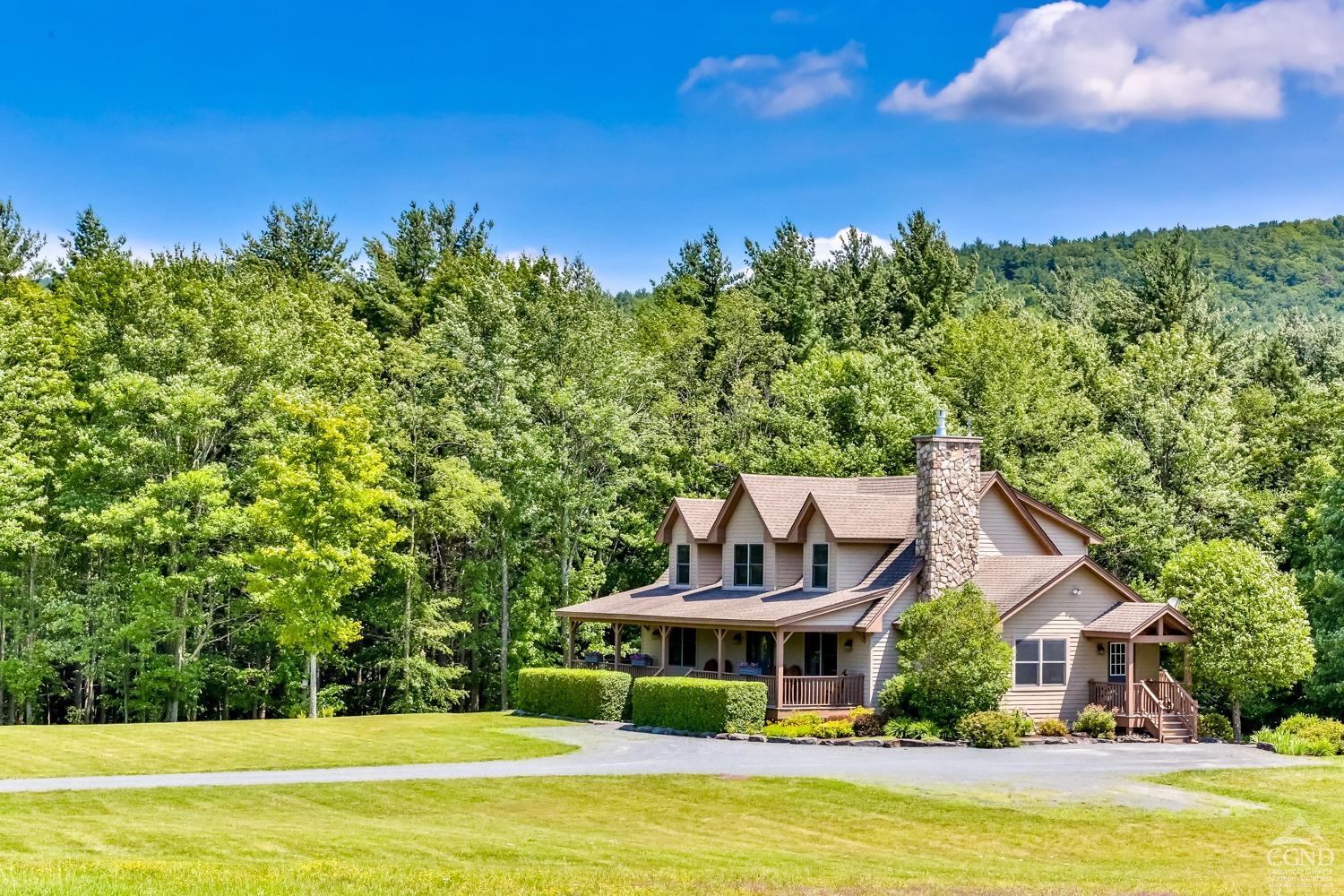 a front view of a house with swimming pool and trees in the background