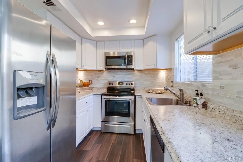 a kitchen with stainless steel appliances granite countertop a sink a stove a refrigerator and a oven