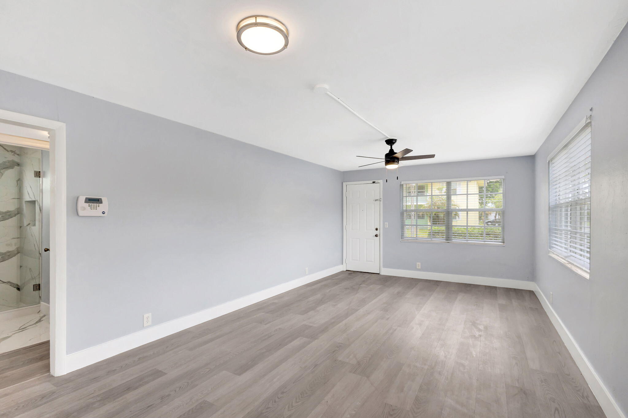 an empty room with wooden floor and windows