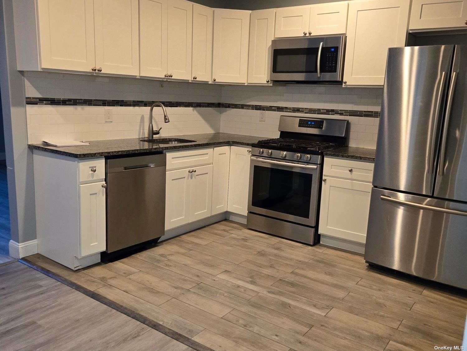 a kitchen with granite countertop a sink stainless steel appliances and cabinets