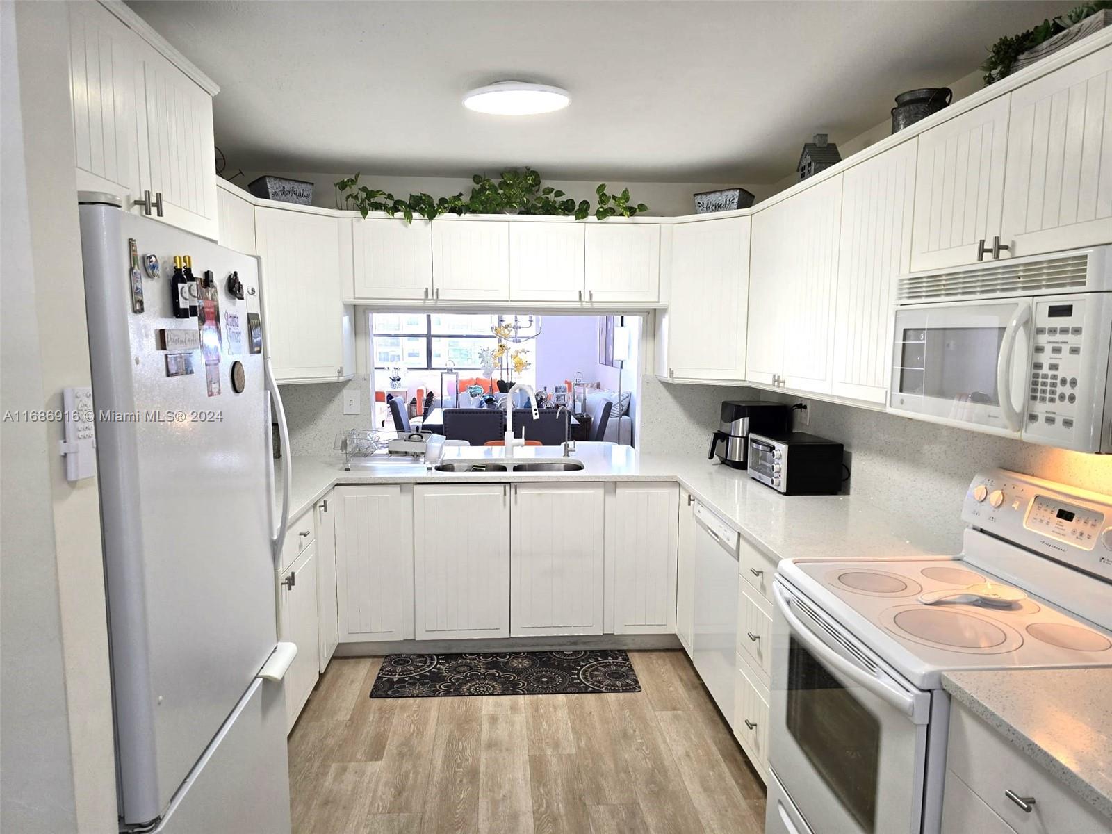 a kitchen with a refrigerator a stove a sink dishwasher and white cabinets with wooden floor