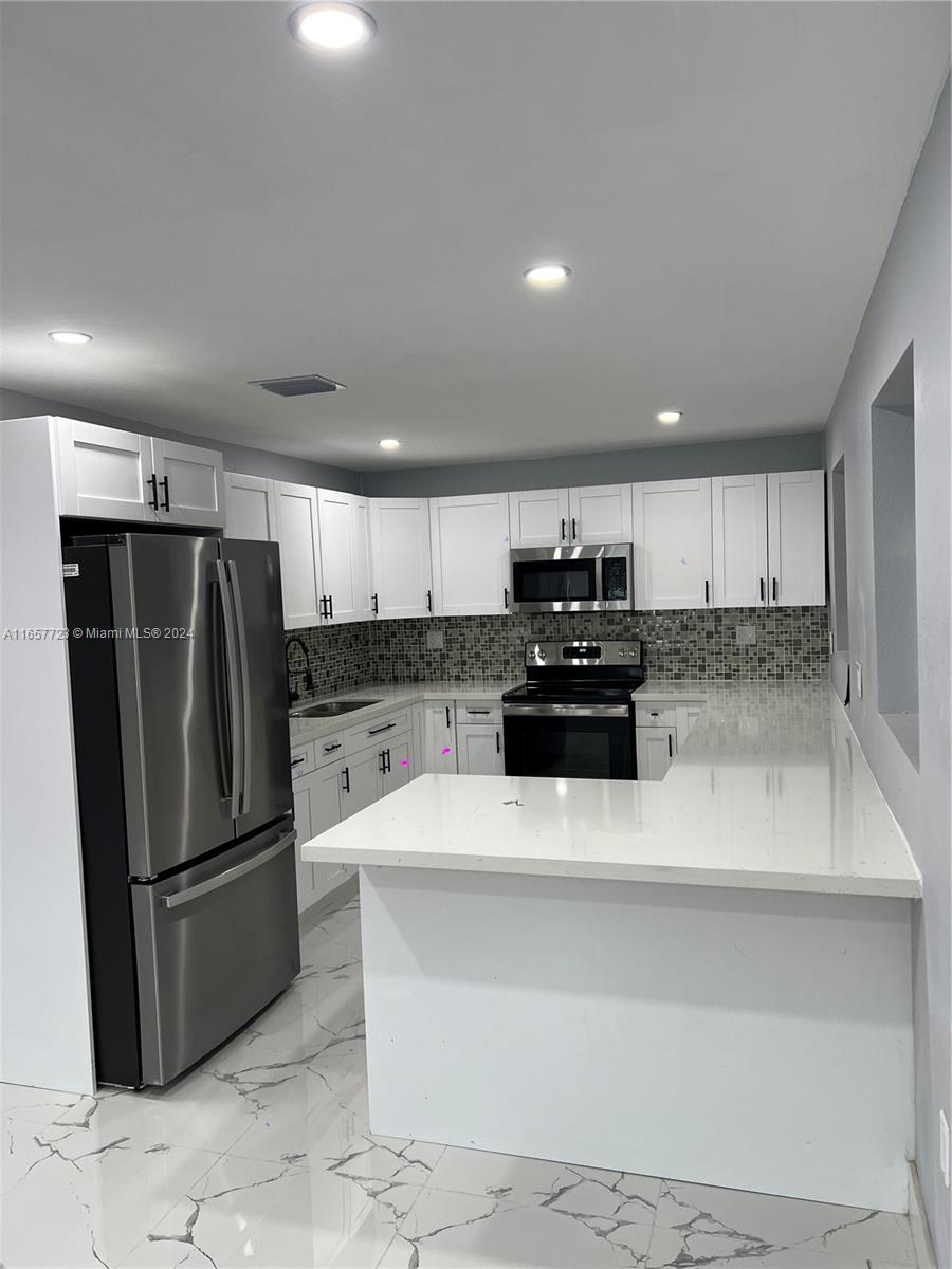 a kitchen with stainless steel appliances granite countertop a refrigerator stove and sink