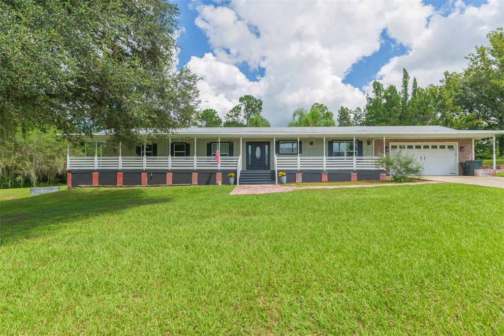 a view of a house with a wooden deck and a big yard