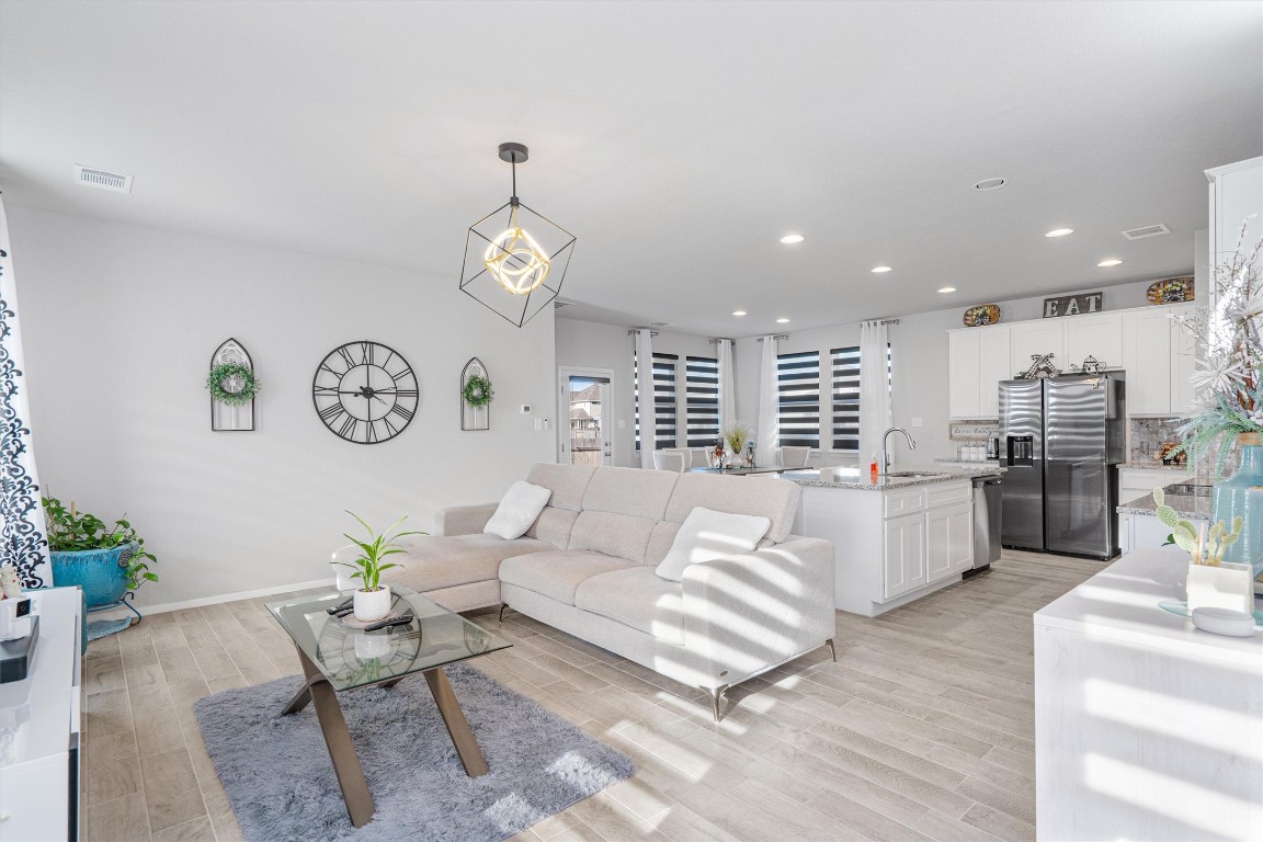 a living room with couches kitchen view and a table