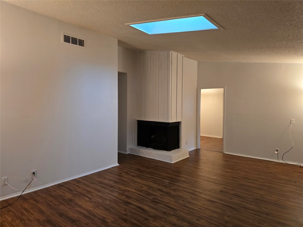 a view of an empty room with wooden floor and a fireplace