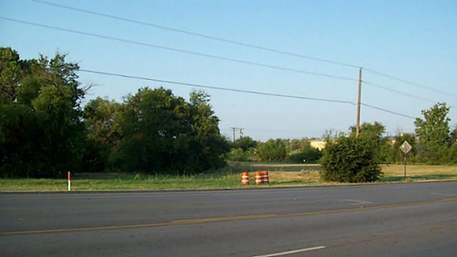 a view of a yard and a car parked on the road