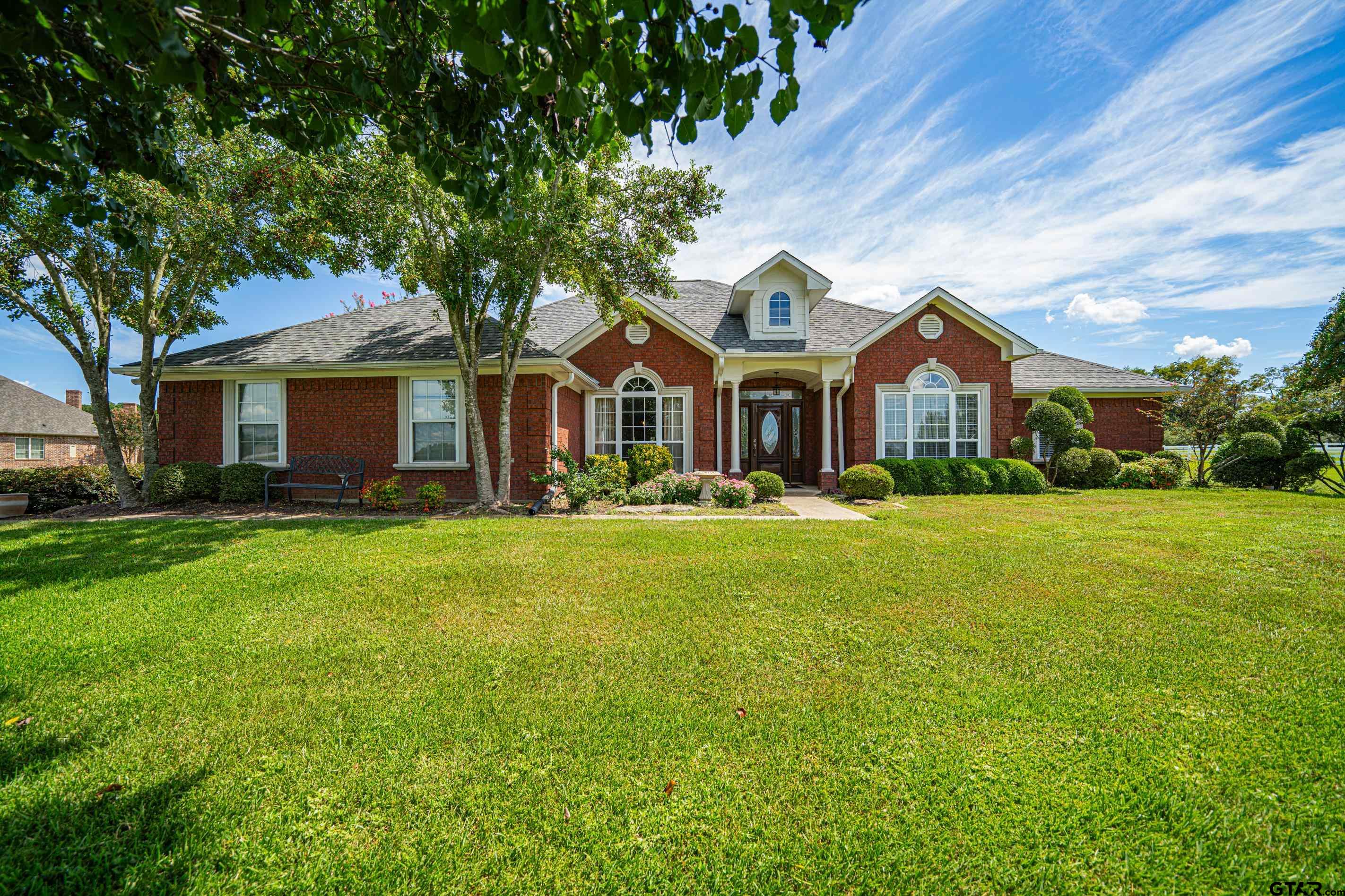 a front view of a house with a garden and trees