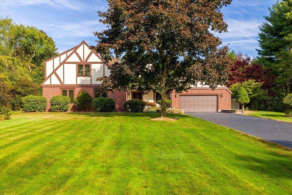 a front view of a house with a yard and tree