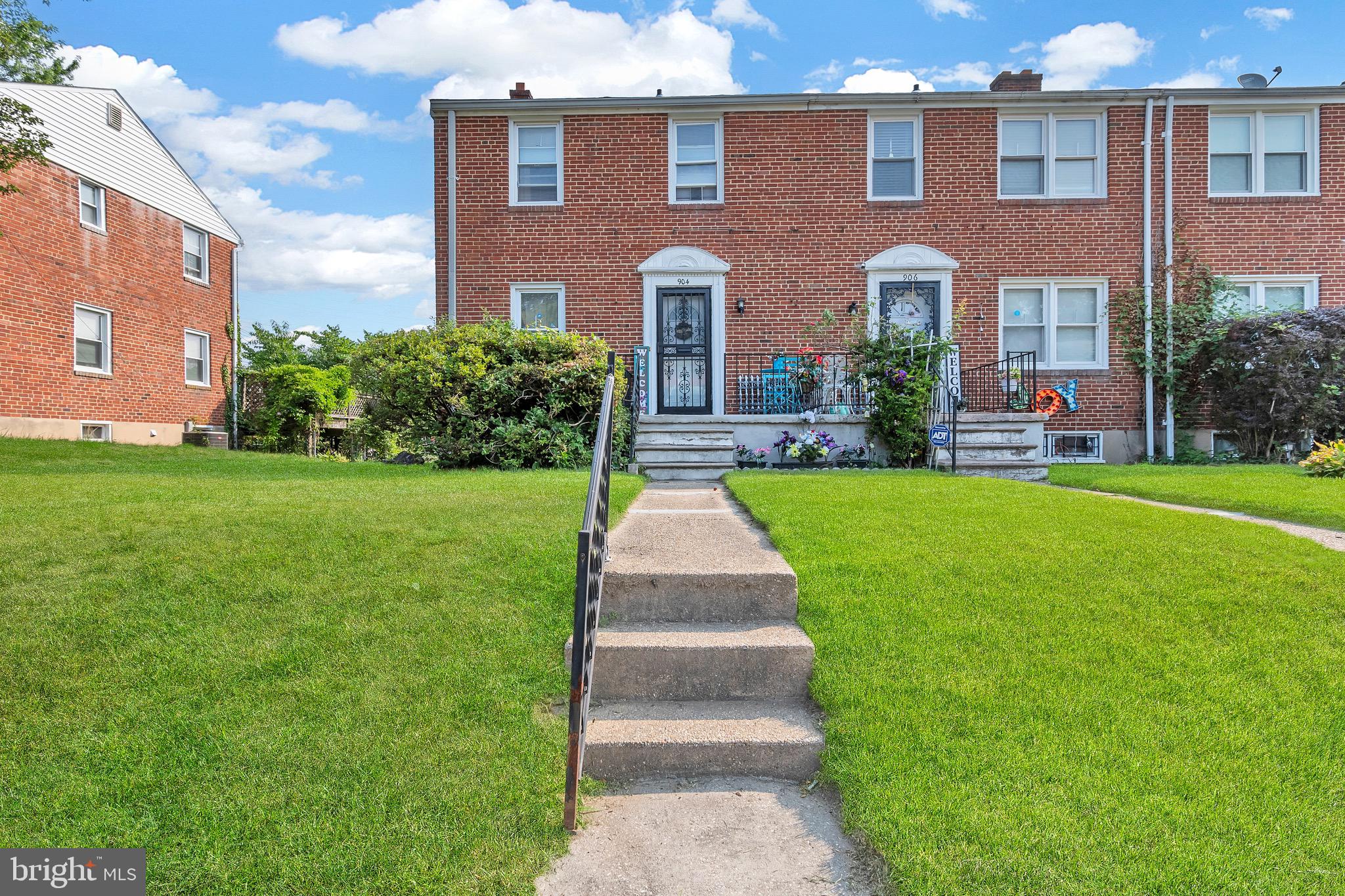 a front view of a brick house with a yard and potted plants