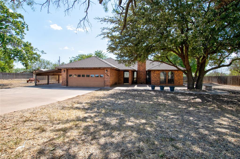 a front view of a house with a yard and large tree