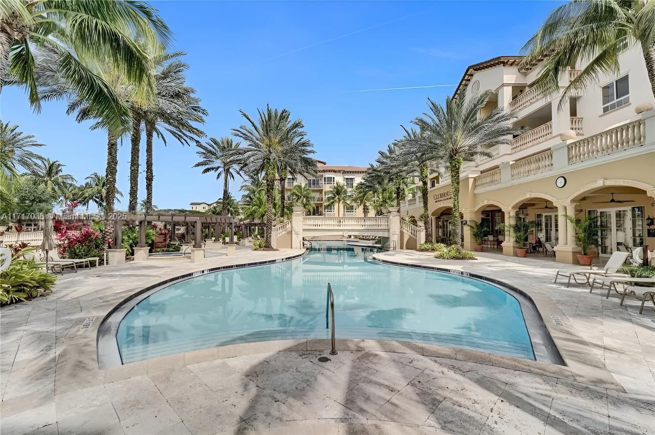 a view of a swimming pool with a lawn chair and palm trees