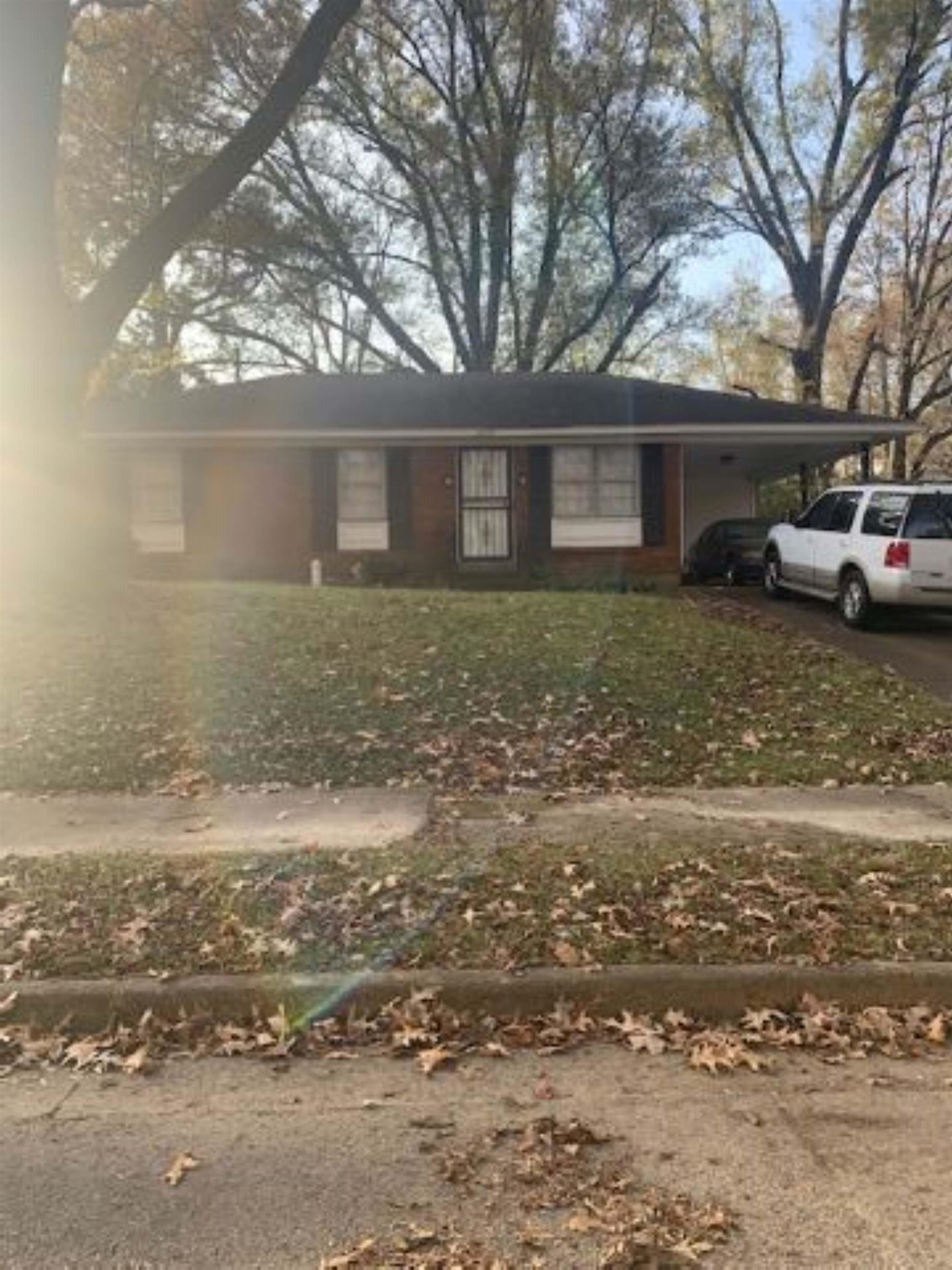 View of front facade featuring a front yard and a carport