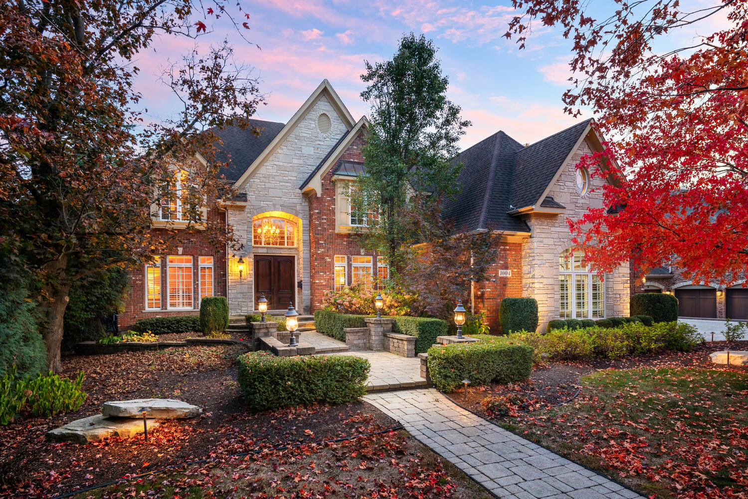 a front view of a house with garden and trees