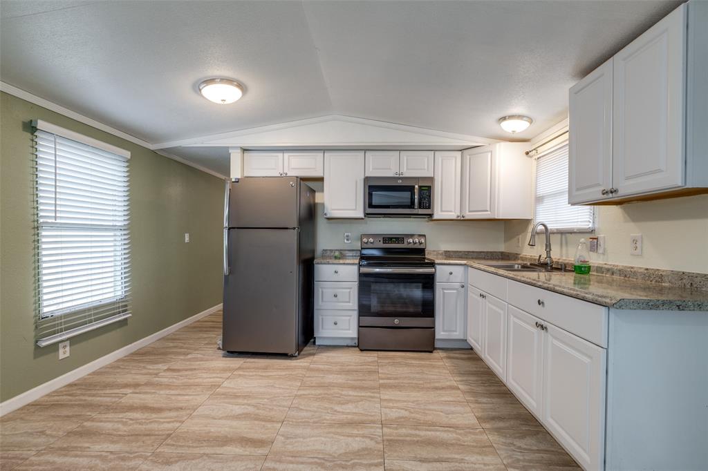 a kitchen with granite countertop a refrigerator and a stove top oven